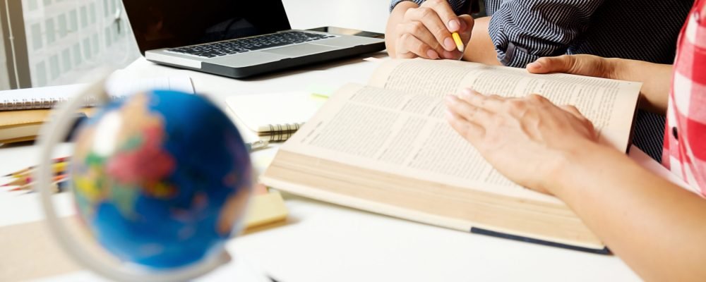 Education concept. Students studying and brainstorming campus concept. Close up of students discussing their subject on books  textbooks and writing to notebook. Seclective focus.
